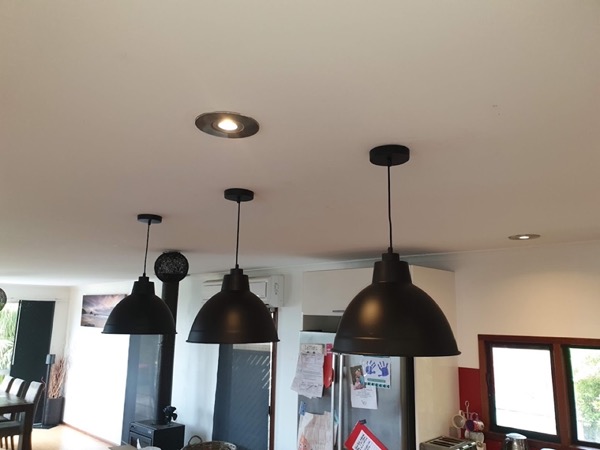 Three black dome pendant lights above a kitchen bench
