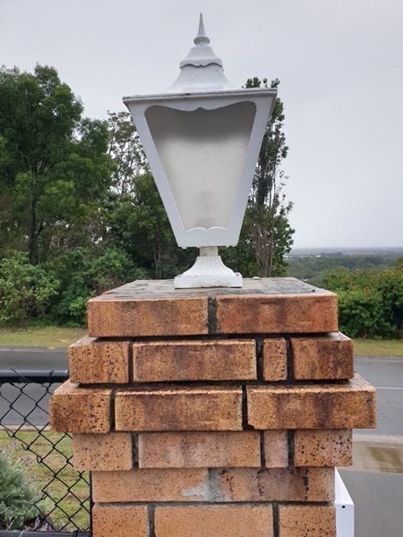 A lantern light mounted on a brick pillar