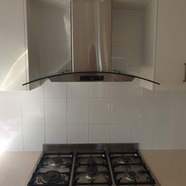 A stainless rangehood above a gas cooktop