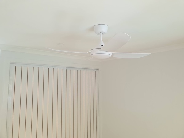 A ceiling fan in a room with vertical blinds