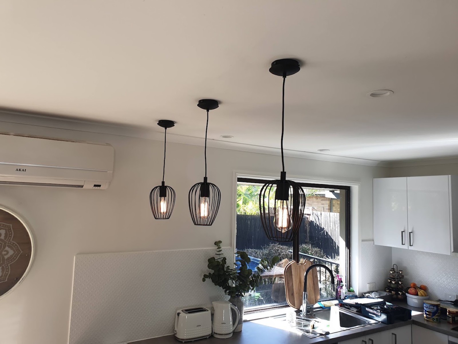 Three caged pendant lights above a kitchen bench