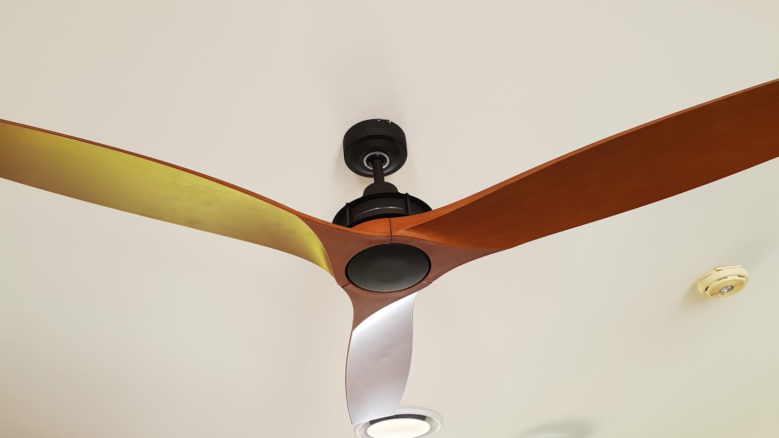 A timber-bladed ceiling fan mounted on a white ceiling