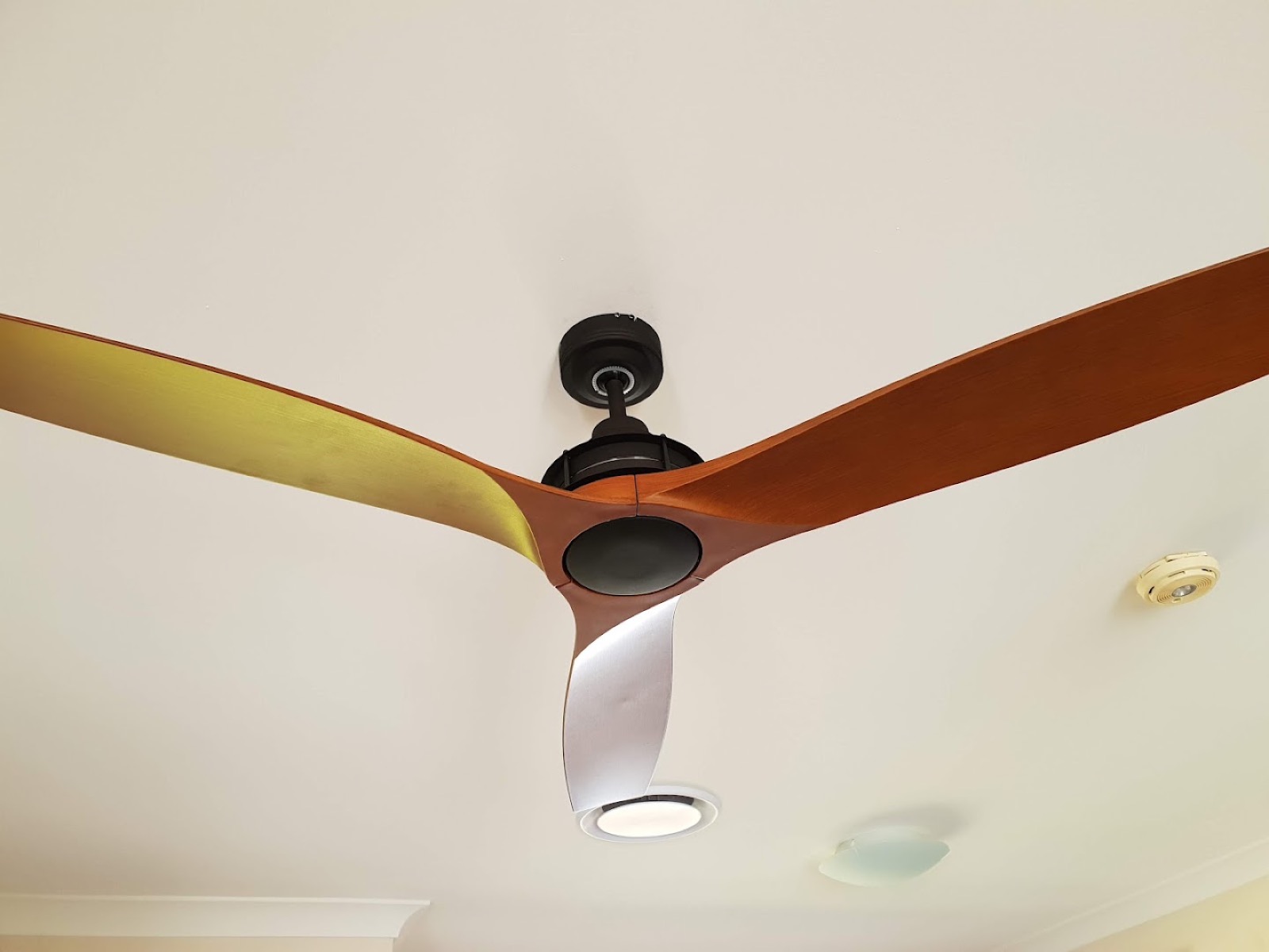 A timber-bladed ceiling fan installed on a white ceiling