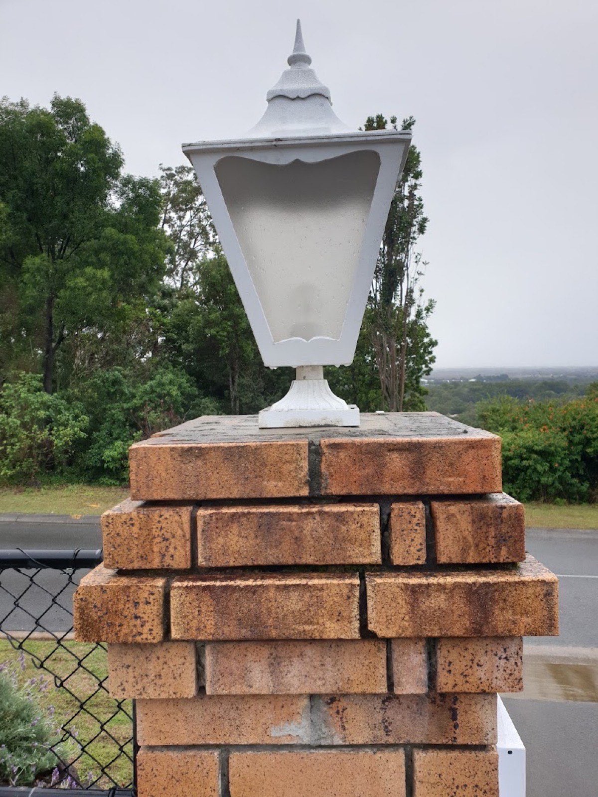A lantern light mounted on a brick pillar